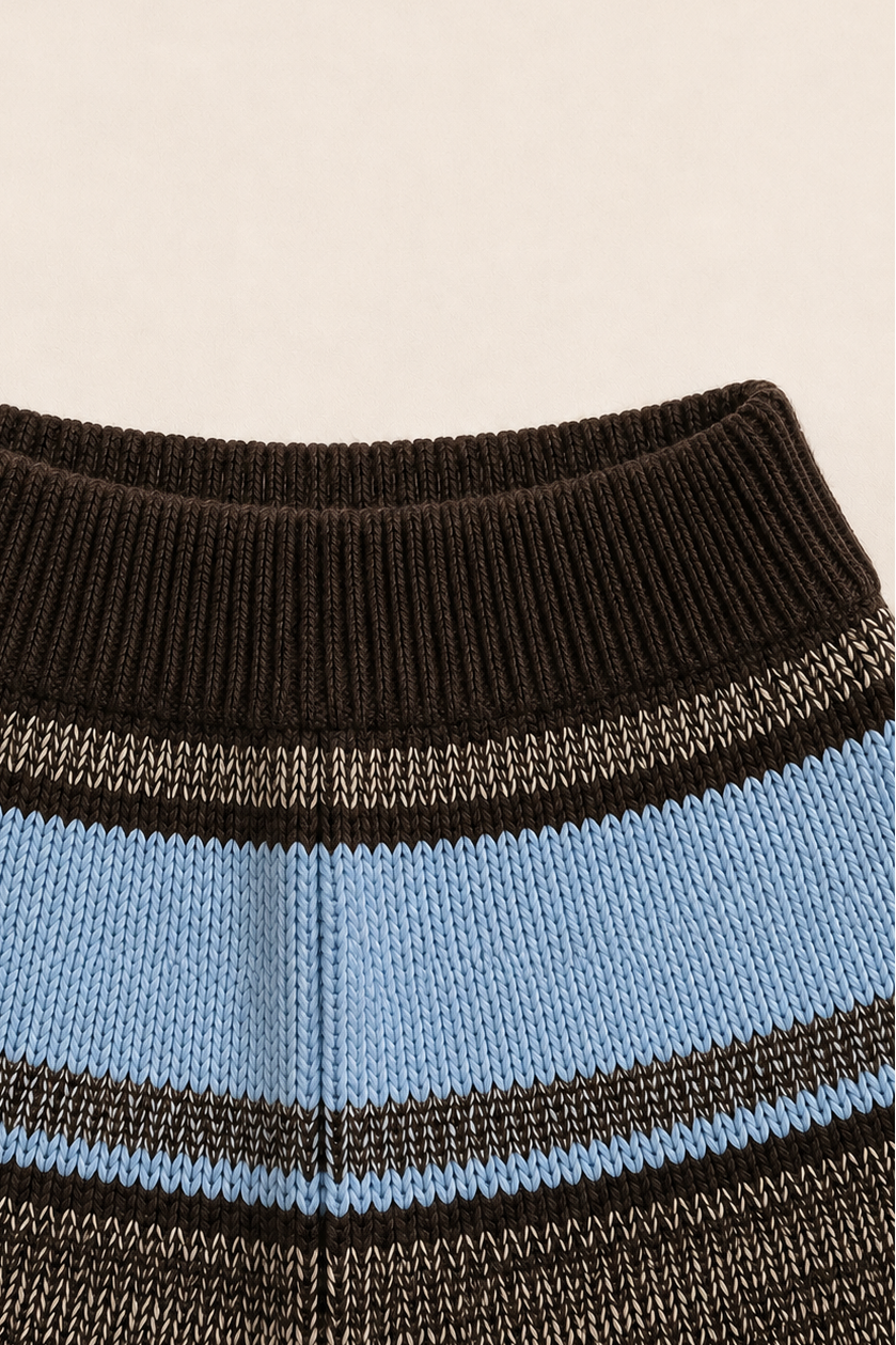 Close-up of a striped knit garment, showing a ribbed dark brown collar with horizontal bands of light blue, dark brown, and black with thin white stripes.