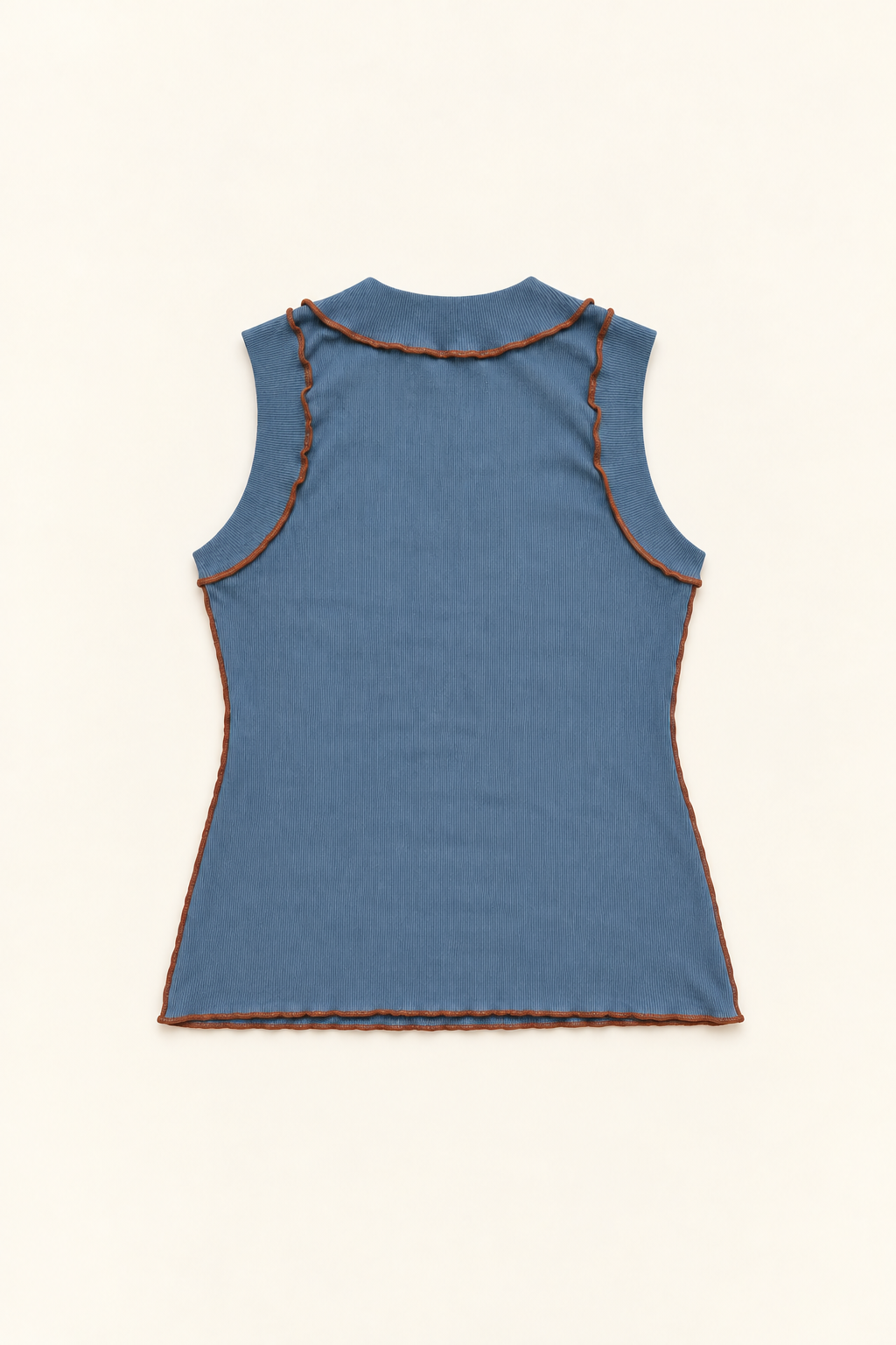 A sleeveless ribbed knit top shown from the back, in a muted slate blue color with contrasting orange-brown piping along the neckline and armholes, laid flat on a light cream background.